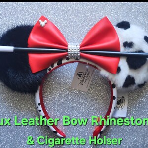 May include: A headband featuring one solid black faux fur ear and one white faux fur ear with black spots. A large red faux leather bow sits in the center, accented by a silver Mickey icon and a rhinestone band. A black and white prop wand is attached.