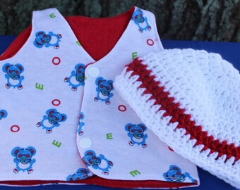 May include: A baby vest and hat set. The vest is white with a pattern of blue teddy bears, red circles, and green letters. The vest has a red lining and white buttons. The hat is white with a red band.