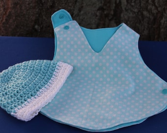 May include: A light blue baby bib with white polka dots and a white crocheted hat. The bib has a V-neck and two snaps on the shoulder.