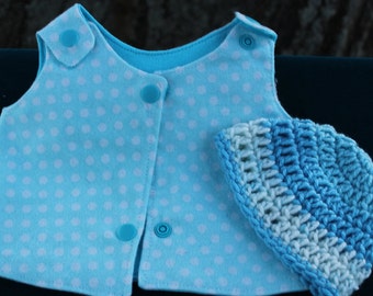 May include: A light blue sleeveless vest featuring a white polka dot pattern and matching blue plastic snap closures, accompanied by a small, round, crocheted hat with alternating horizontal stripes of light blue and white yarn.