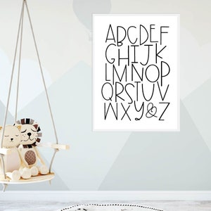 May include: A white framed print with black text that reads "ABCDEFGHIJKLMNOPQRSTUVWXYZ&" in a simple, modern font.
