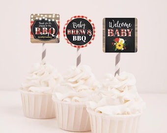 May include: Three cupcakes with white frosting topped with red and white checkered, woodgrain, and chalkboard cupcake toppers. The toppers say "Thank you for coming to our BBQ", "Baby Brew & BBQ", and "Welcome Baby".