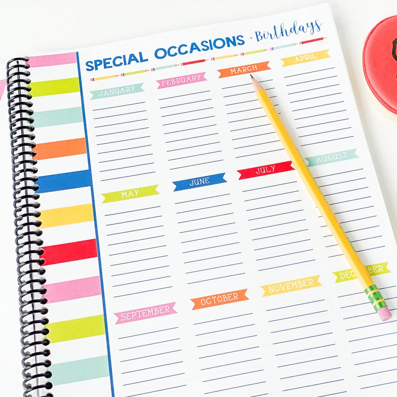 Pode incluir: Uma agenda branca com uma capa listrada colorida e uma encaderna&ccedil;&atilde;o em espiral preta. A agenda tem uma se&ccedil;&atilde;o para ocasi&otilde;es especiais e anivers&aacute;rios, com cada m&ecirc;s rotulado em uma faixa colorida. Os meses s&atilde;o janeiro, fevereiro, mar&ccedil;o, abril, maio, junho, julho, agosto, setembro, outubro, novembro e dezembro.