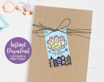 以下が含まれることがあります： 「So Super!」と書かれた青と黄色のギフトタグが付いた茶色のギフトバッグ。街並みと「From Adriana & Isaiah」の文字が書かれています。