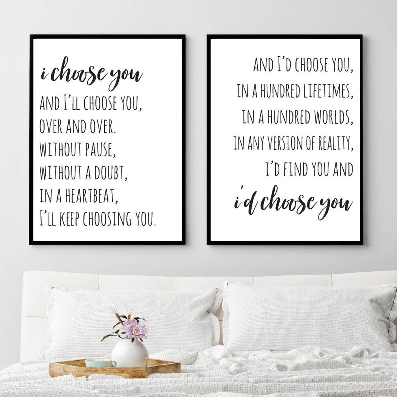 May include: Two black framed prints with white backgrounds and black text. The left print reads "i choose you AND I'LL CHOOSE YOU, OVER AND OVER. WITHOUT PAUSE, WITHOUT A DOUBT, IN A HEARTBEAT, I'LL KEEP CHOOSING YOU." The right print reads "AND I'D CHOOSE YOU, IN A HUNDRED LIFETIMES, IN A HUNDRED WORLDS, IN ANY VERSION OF REALITY, I'D FIND YOU AND i'd choose you".