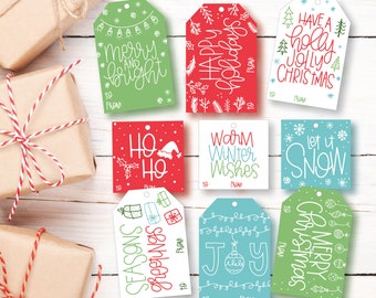Puede incluir: Nueve etiquetas de regalo de Navidad coloridas con varios saludos navideños e ilustraciones. Las etiquetas están impresas en cartulina blanca con tinta roja, verde y azul. Las etiquetas presentan diseños festivos como copos de nieve, árboles de Navidad, adornos y un gorro de Papá Noel. El texto en las etiquetas incluye frases como "Feliz y brillante", "Felices fiestas", "Cálidos deseos de invierno", "Deja que nieve", "Saludos de temporada", "Alegría" y "Feliz Navidad".