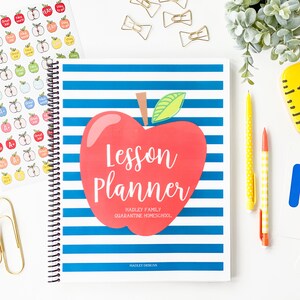 Pode incluir: Um caderno azul e branco listrado com uma ma&ccedil;&atilde; vermelha na capa. A ma&ccedil;&atilde; tem as palavras "Lesson Planner" escritas nela. O texto abaixo da ma&ccedil;&atilde; diz "Hadley Family Quarantine Homeschool" e "Hadley Designs".