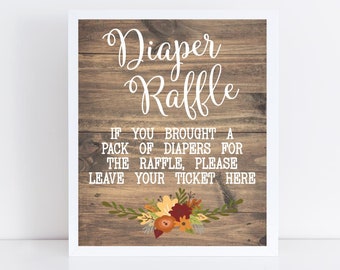 Könnte beinhalten: Ein weiß gerahmtes Schild mit Holzmaserung im Hintergrund und dem Text "Diaper Raffle" in weißer Kursivschrift. Der Text darunter lautet "Wenn Sie eine Packung Windeln für die Tombola mitgebracht haben, hinterlassen Sie bitte Ihr Ticket hier". Das Schild ist mit einem Blumenkranz in Herbstfarben verziert.