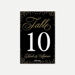 May include: Black table number card with gold confetti and white text. The card says "Table 10" and "Nicole & Antonio".