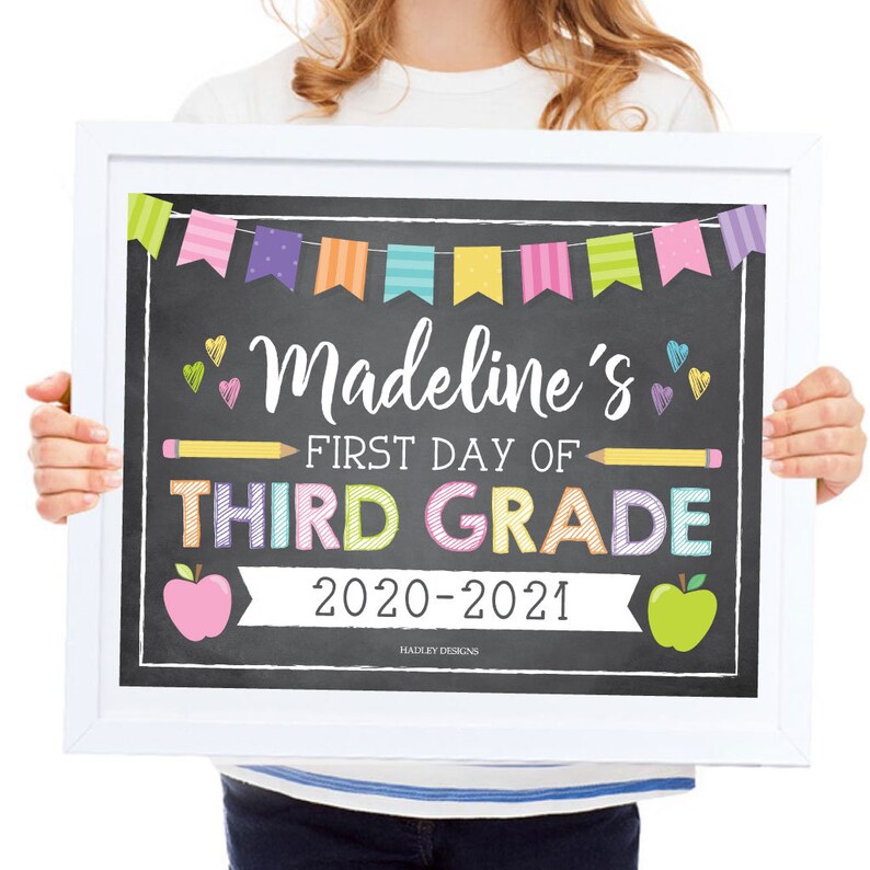 May include: A chalkboard sign with colorful bunting, a pencil, and apples. The sign reads "Madeline's First Day of Third Grade 2020-2021".