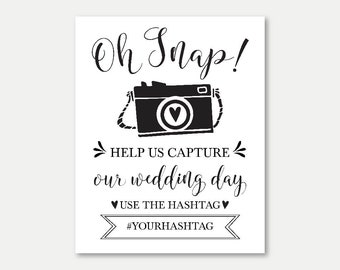 Puede incluir: Señal imprimible en blanco y negro con el texto "Oh Snap!" y una cámara de dibujos animados con un corazón en el objetivo. El cartel dice "Ayúdanos a capturar nuestro día de boda. Usa el hashtag #YOURHASHTAG"