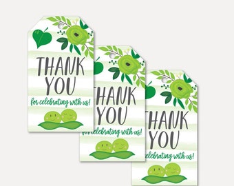 Op de afbeelding: Drie groene en witte gestreepte cadeau-etiketten met een bloemenontwerp en de tekst "THANK YOU for celebrating with us!" en een paar groene erwten met lachende gezichten.