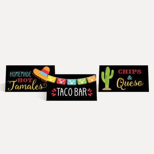 Może przedstawiać: Trzy czarne tablice z czarnej tablicy z kolorowym tekstem i grafiką. Tablice głosiły "Homemade Hot Tamales", "Taco Bar" z ciągiem kolorowych flag i "Chips & Queso" z zielonym kaktusem.