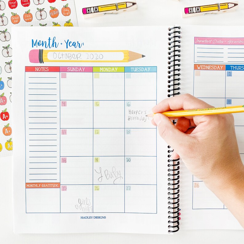 Pode incluir: Um planejador mensal com uma capa colorida e um l&aacute;pis no topo. O planejador tem um calend&aacute;rio para outubro de 2020 com se&ccedil;&otilde;es de notas, gratid&atilde;o mensal e datas importantes. O calend&aacute;rio tem entradas escritas &agrave; m&atilde;o para anivers&aacute;rios e outros eventos.