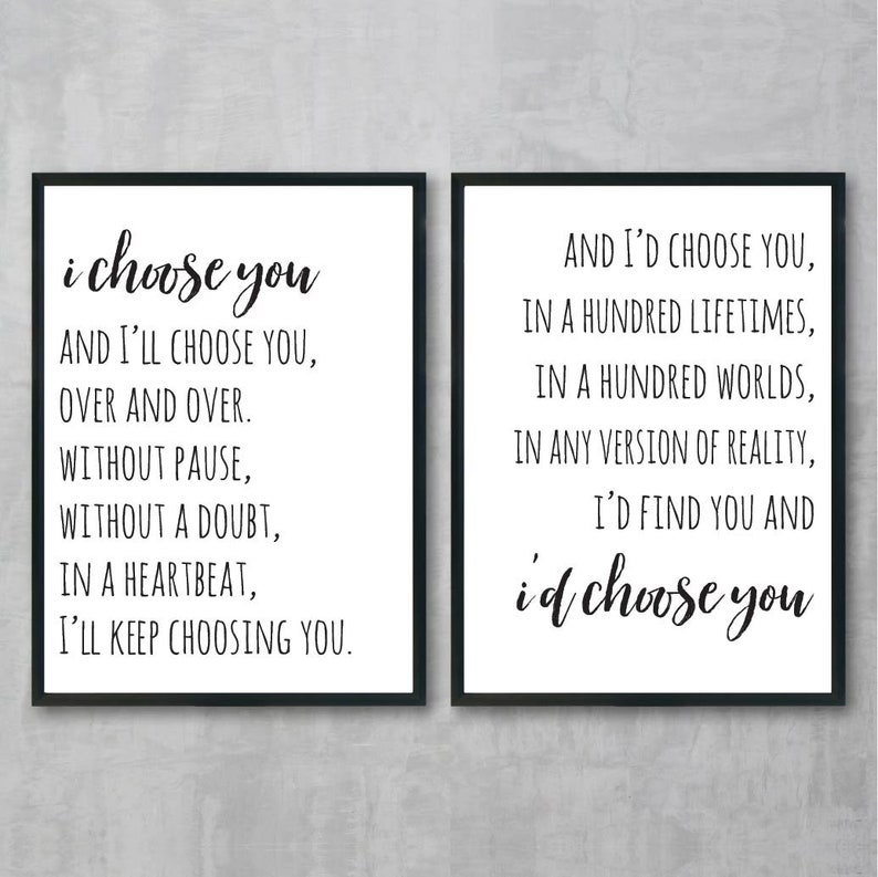 May include: Two black framed prints with white backgrounds and black text. The left print reads "i choose you" and the right print reads "AND I'D CHOOSE YOU, IN A HUNDRED LIFETIMES, IN A HUNDRED WORLDS, IN ANY VERSION OF REALITY, I'D FIND YOU AND i'd choose you".