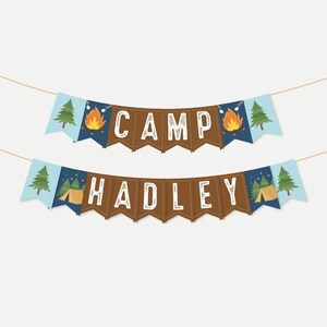 Op de afbeelding: Een bruin en blauwe campingbanner met de tekst "CAMP HADLEY" in wit. De banner bevat illustraties van dennenbomen, kampvuren en tenten.