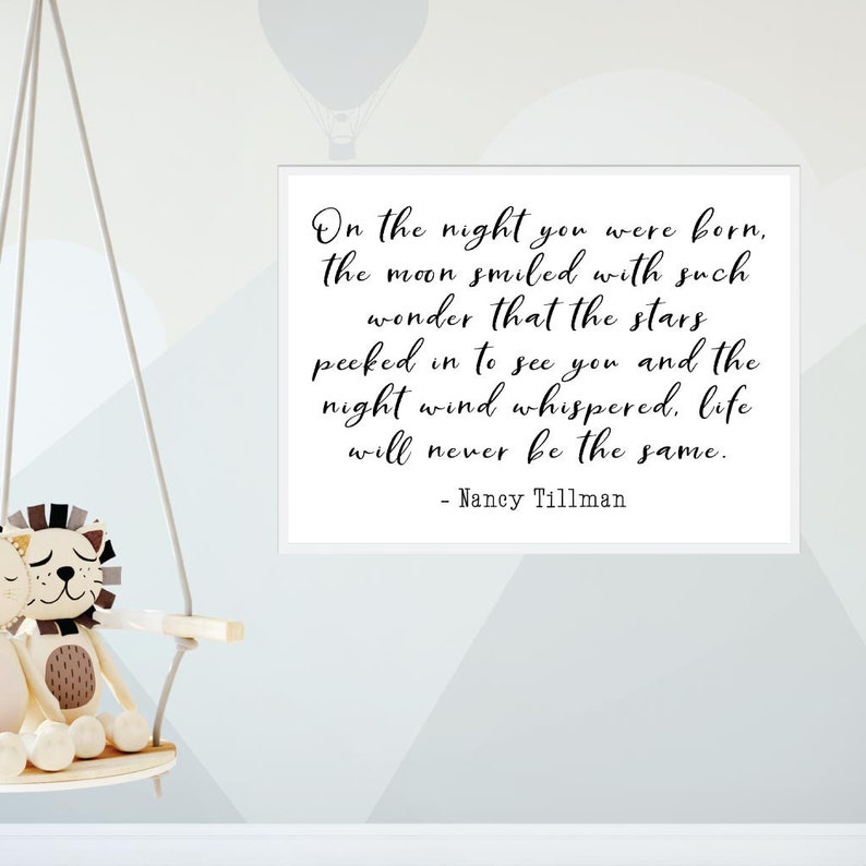Op de afbeelding: Een wit ingelijst print met een zwart-wit citaat dat luidt: "On the night you were born, the moon smiled with such wonder that the stars peeked in to see you and the night wind whispered, life will never be the same." - Nancy Tillman