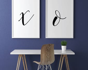 Puede incluir: Dos impresiones enmarcadas blancas con caligrafía negra sobre fondo blanco. Las impresiones están colgadas en una pared azul sobre una mesa blanca con una silla de madera y una planta sobre la mesa.