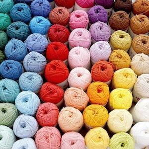 May include: A collection of colorful yarn balls in various shades, including blue, red, pink, yellow, and green. The yarn is neatly arranged, showcasing a variety of hues and textures, perfect for knitting and crochet projects.