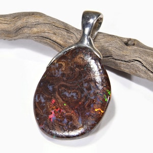 May include: A silver pendant with a brown, red, and green opal stone. The opal has a textured surface and is set in a silver bail.