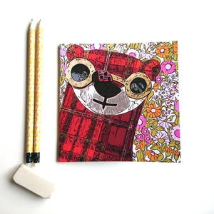 May include: A red and black plaid notebook featuring a cartoon bear wearing round glasses against a floral background.