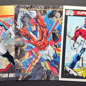 May include: Three Captain Britain trading cards. The cards feature illustrations of the superhero in action poses. The cards have a red, white, blue, and black color scheme. The words "SUPER HEROES" and "CAPTAIN BRITAIN" are visible.