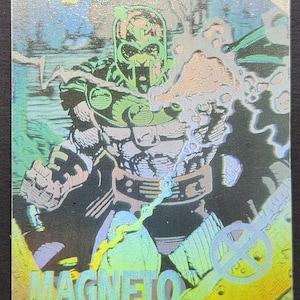 May include: A holographic trading card featuring the Marvel Comics character Magneto. The illustration depicts Magneto in a dynamic pose, with a green helmet and armor. The card has a shiny, iridescent finish, with the word "MAGNETO" at the bottom.