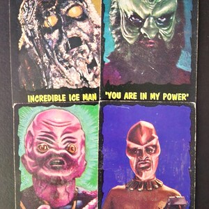 May include: Four vintage trading cards featuring alien characters. The cards display colorful illustrations of extraterrestrial beings with text such as "INCREDIBLE ICE MAN" and "INVADE EARTH". The cards have a retro aesthetic.
