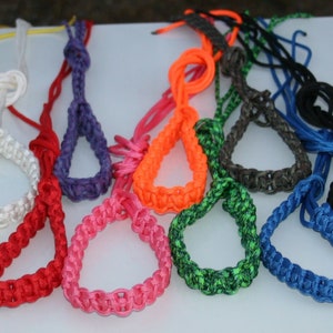 Puede incluir: Un conjunto de diez cordones de muñeca trenzados de colores en varios colores, incluidos amarillo, rojo, rosa, naranja, verde, azul y negro.