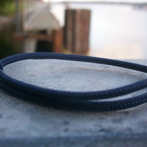 Könnte beinhalten: Ein dunkelblaues Seil-Armband mit einem einfachen Knotendesign.