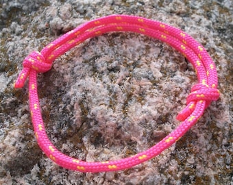 Peut inclure: Un bracelet en corde tressée rose et jaune avec un nœud à une extrémité.