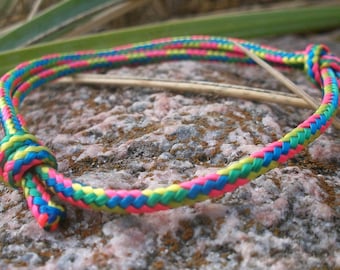 Peut inclure: Un bracelet tressé coloré avec des fils roses, bleus, verts et jaunes. Le bracelet est noué à l'extrémité.