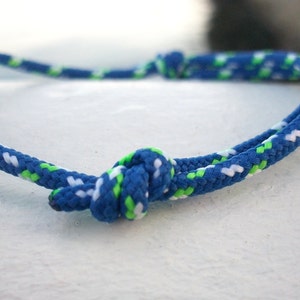 Könnte beinhalten: Ein blaues, weißes und grünes Seil-Armband mit einem Knoten in der Mitte.