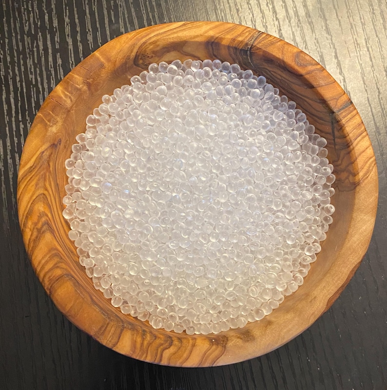 May include: A bowl filled with clear silica gel beads, commonly used for absorbing moisture and preventing damage to items.