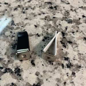 May include: Two car air freshener clips, one black and one white. The clips are made of plastic and have a metal clip to hold the air freshener.