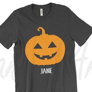 May include: A dark gray t-shirt with an orange jack-o'-lantern face and the name "JANE" printed below it.