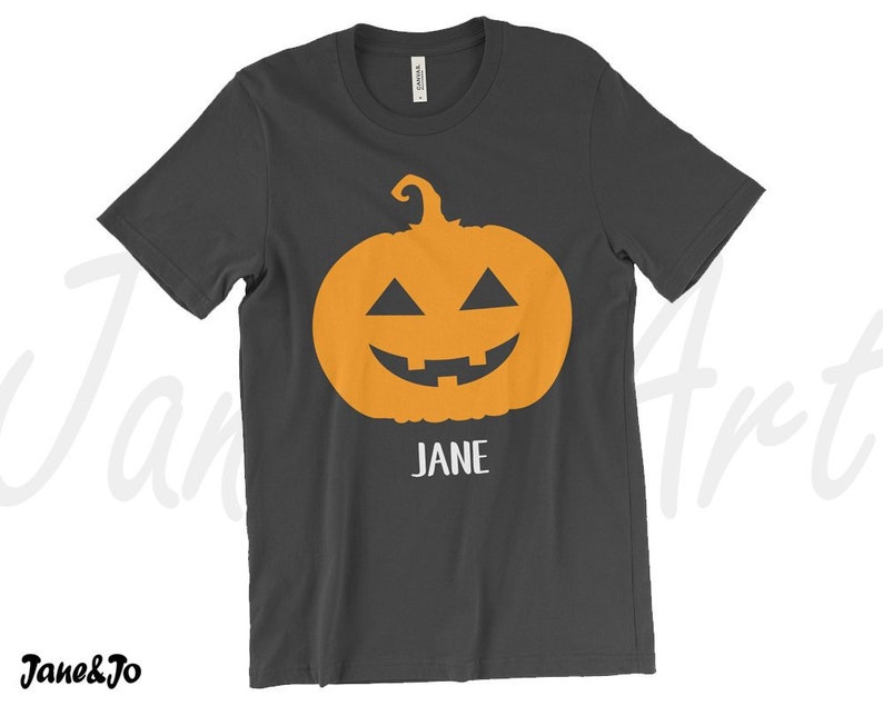 May include: A dark gray t-shirt with an orange jack-o'-lantern face and the name "JANE" printed below it.