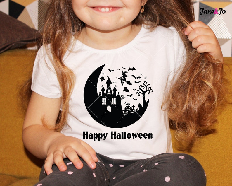May include: A white t-shirt with a black silhouette of a crescent moon, a haunted house, a witch flying on a broomstick, bats, a ghost, a tree, and pumpkins. The text "Happy Halloween" is printed below the moon.