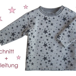 Pode incluir: Uma camisa cinza de manga comprida com um padrão de estrelas pretas. A camisa tem um decote canelado e está etiquetada como "Schnitt + Anleitung".