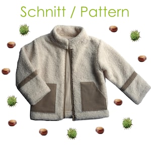 Op de afbeelding: Een crèmekleurig, getextureerd fleecejack met een opstaande kraag, een centrale ritssluiting en twee bruine rechthoekige zakken. De mouwen hebben bruine horizontale banden. De tekst "Schnitt / Pattern" staat boven het jack, omringd door kastanjes.