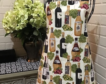 Wine bottle theme adult apron with various wine bottles, grapes, and leaves.