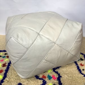 Op de afbeelding: Een witte leren poef met een ruitvormig gestikt patroon. De poef is gemaakt van zacht, soepel leer en heeft een comfortabel, gestoffeerd gevoel.