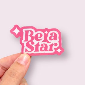 May include: Pink sticker with white text that reads "Be a Star" with a small white star in the corner.