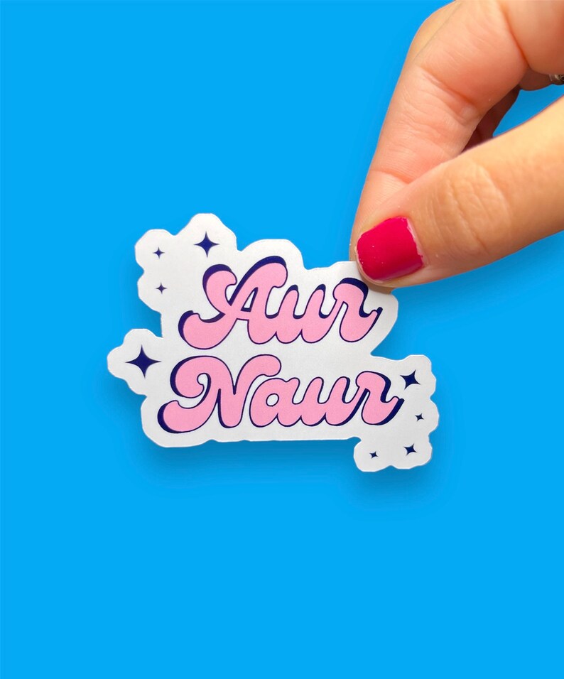 Peut inclure: Un autocollant blanc avec un lettrage rose et bleu qui dit "Aur Naur" avec de petites &eacute;toiles blanches autour du texte.