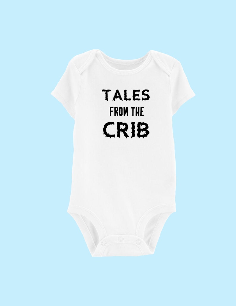 K&ouml;nnte beinhalten: Wei&szlig;er Baby-Strampler mit schwarzem Text, der "Tales from the Crib" lautet.