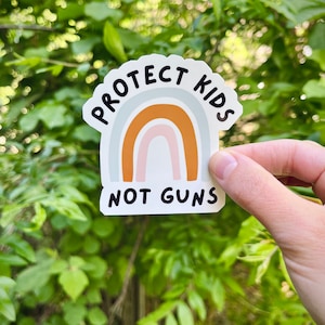 May include: A white sticker with a rainbow design and the text "Protect Kids Not Guns".
