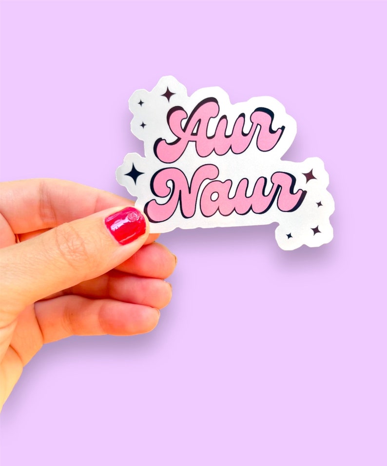 Peut inclure: Un autocollant rose et blanc avec le texte "Aur Naur" dans une police r&eacute;tro. L'autocollant a de petites &eacute;toiles noires autour du texte.