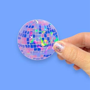 May include: A clear iridescent sticker of a disco ball with pink and blue squares and rainbow glitter.