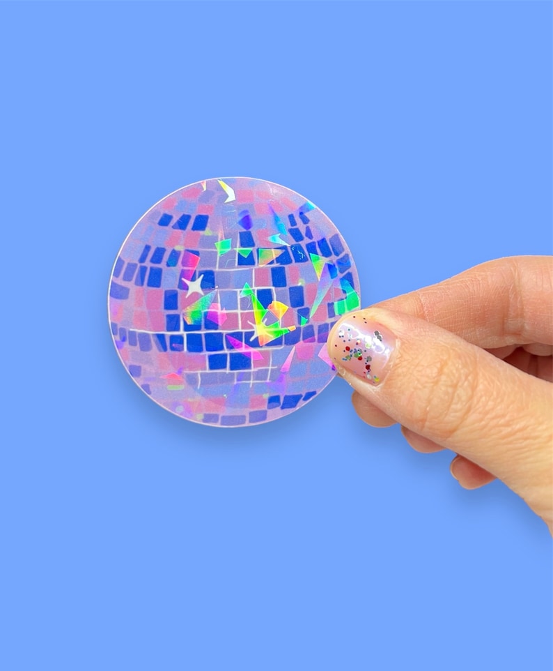 May include: A clear iridescent sticker of a disco ball with pink and blue squares and rainbow glitter.