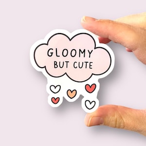 May include: A white sticker with a pink cloud that says "Gloomy but cute" and has five small hearts in different colors falling from it.